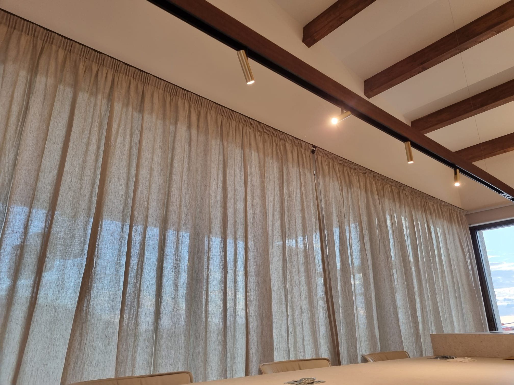Floor-to-ceiling translucent curtains beneath a timber-beamed ceiling