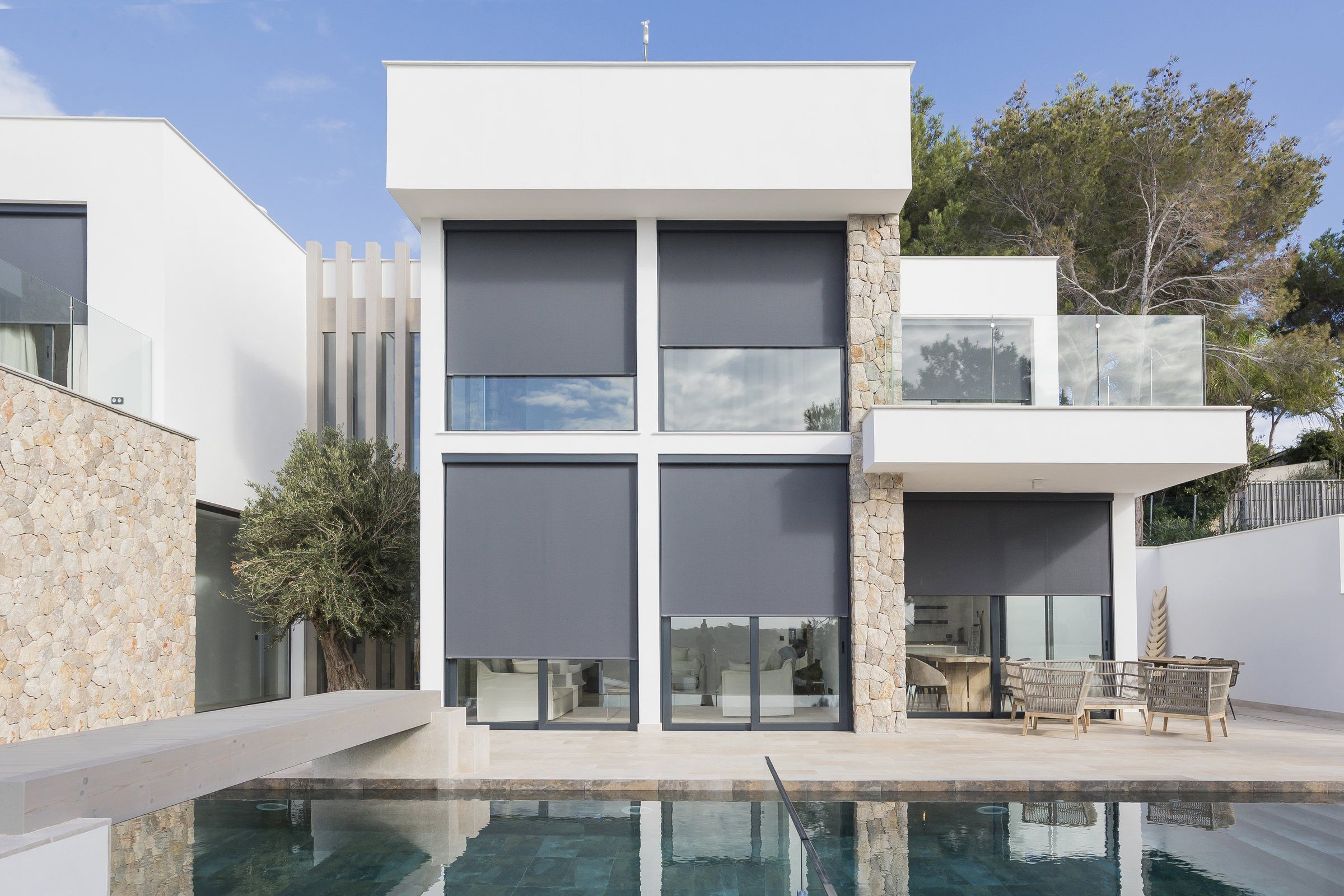 Weiße Fassade mit grauen B-Box-Rollos am Pool