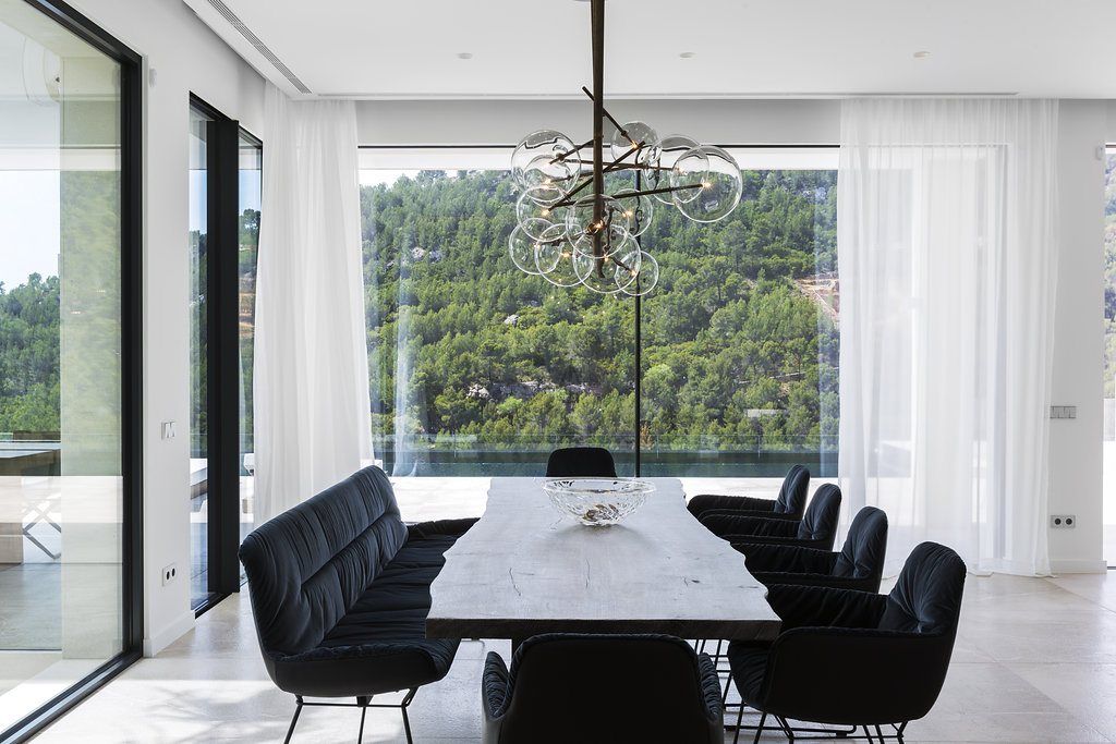 Dining room with white sheers in front of a large window with views