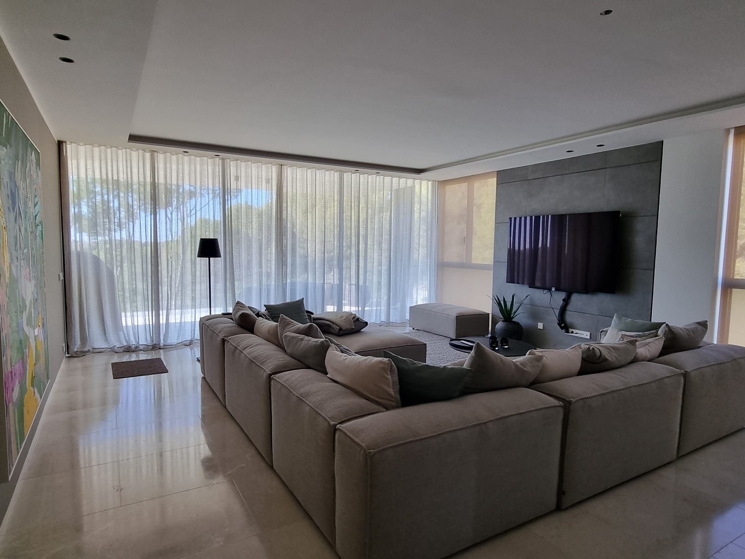 Wohnbereich mit großem Sofa und Wellenvorhängen entlang der Fensterfront