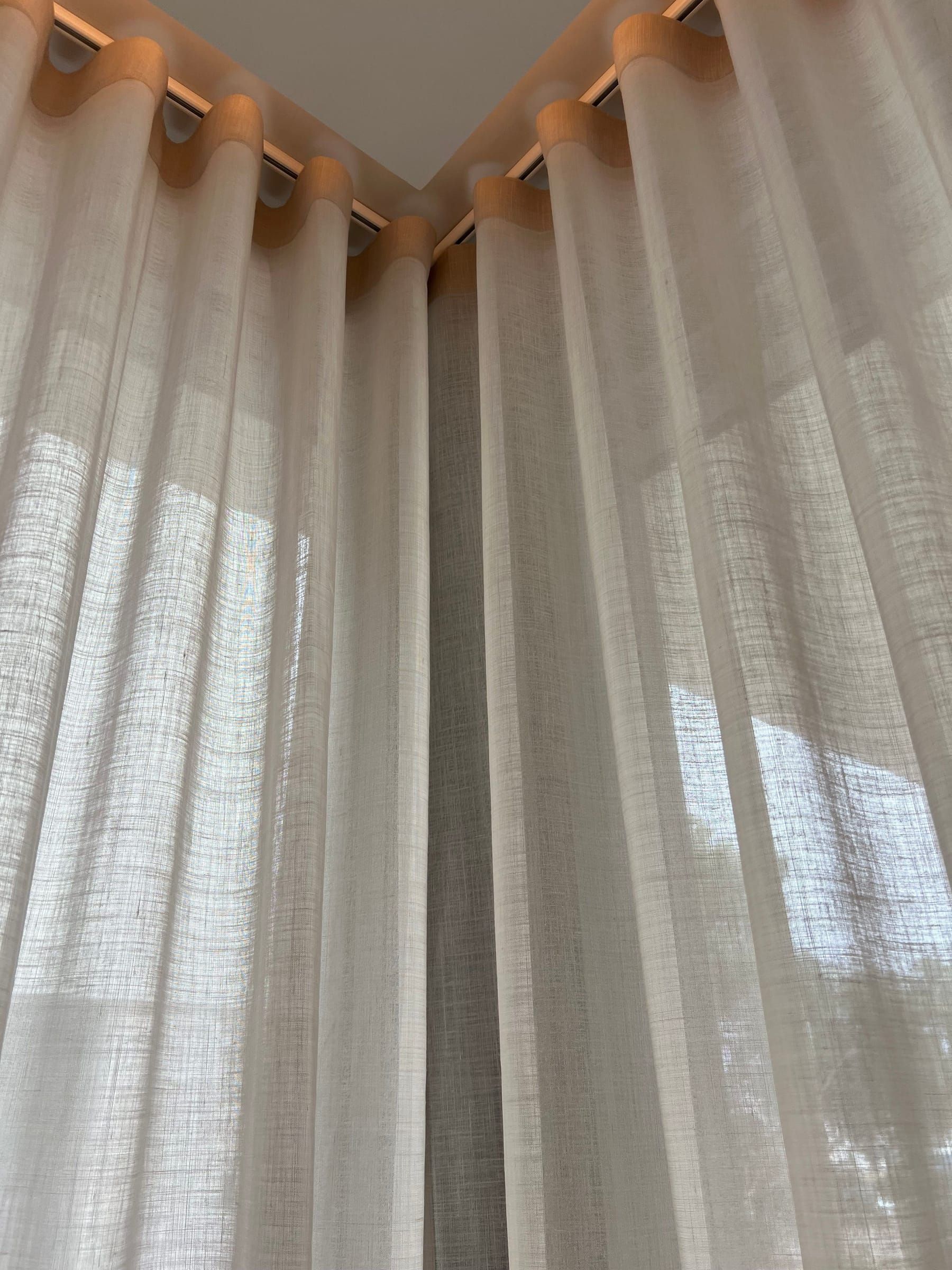 Esquina donde se unen dos cortinas de visillo con caída hasta el suelo