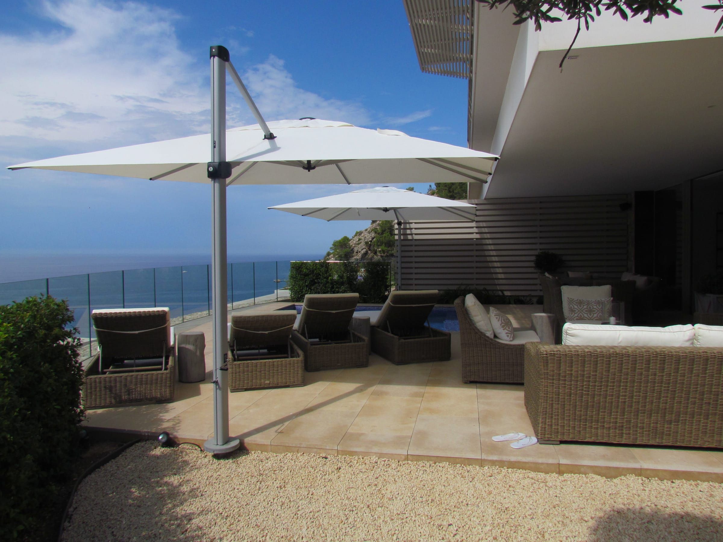 Two parasols over the sun loungers and sofas on the sea-facing terrace