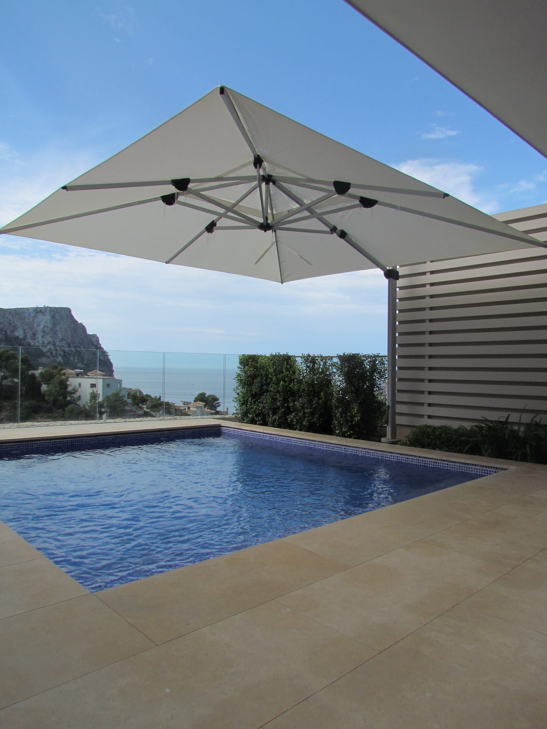 Open parasol over the pool with the cliff and the sea behind