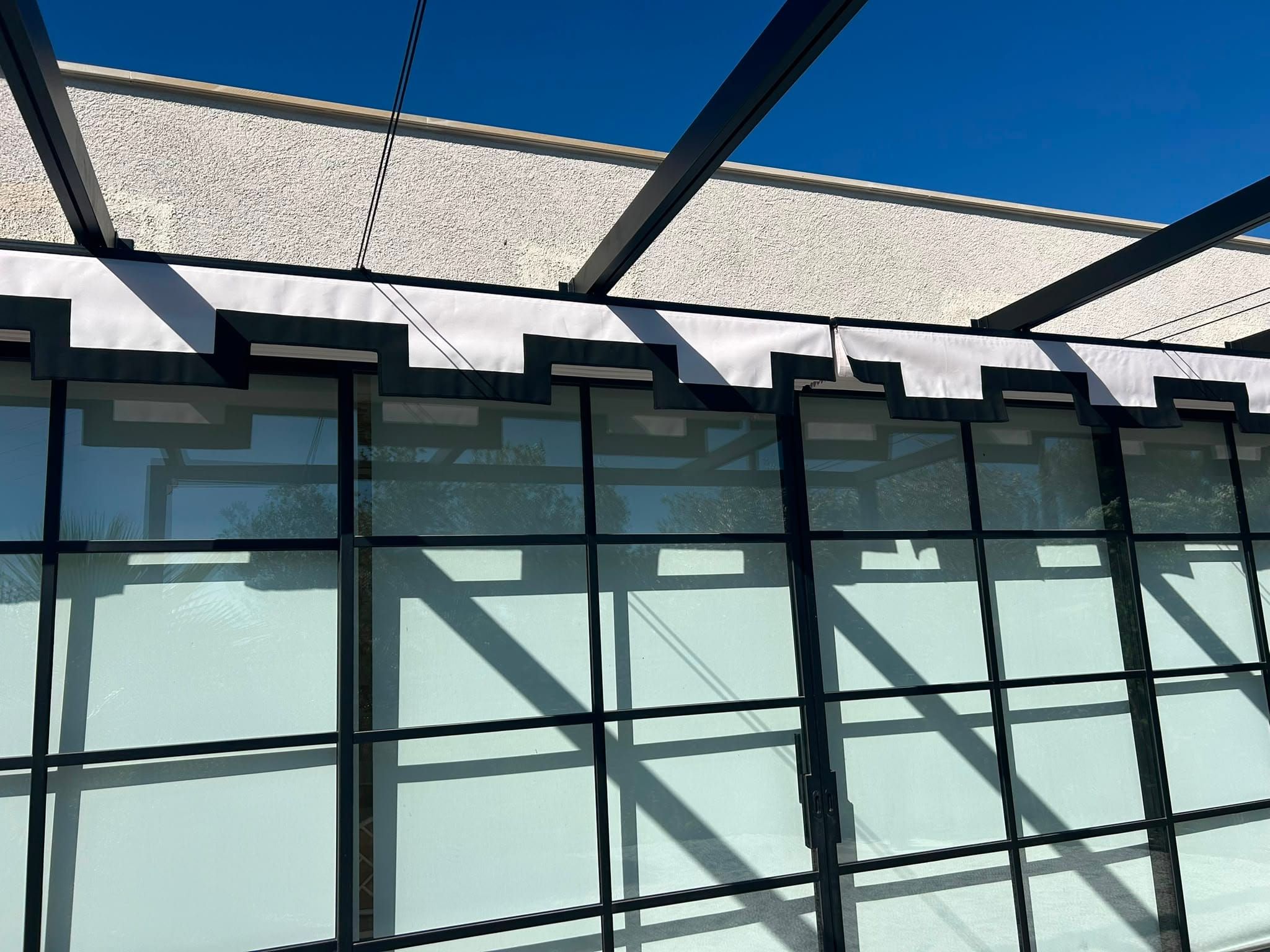 Eingefahrene Faltmarkise über der Fensterfront mit sichtbarem Metallgestell