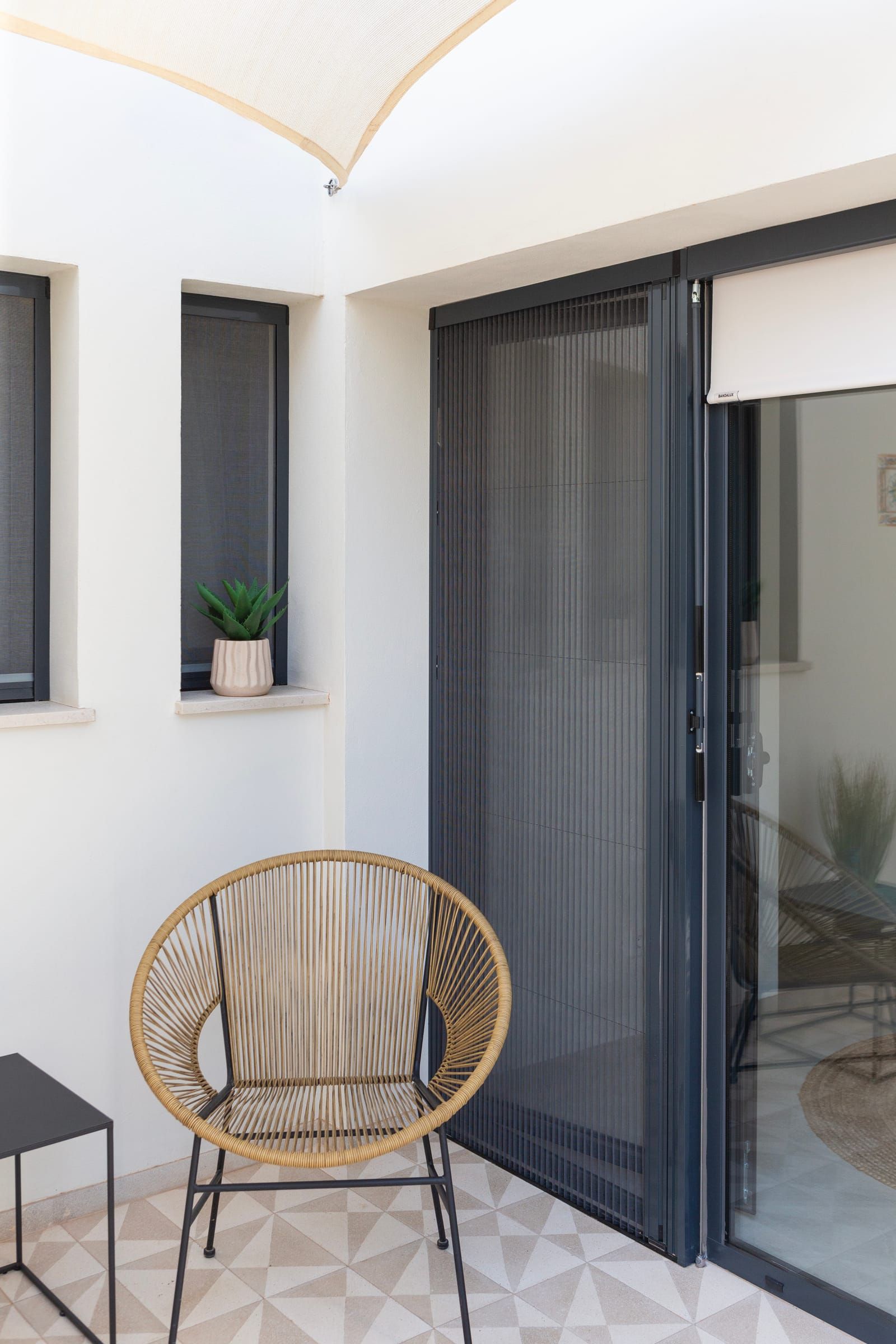 Patio with a rattan chair, sliding door and windows with insect screens